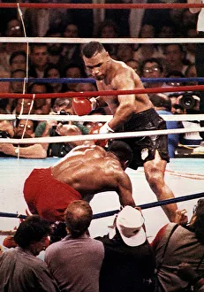 Mike Tyson Heavyweight Boxer stands over the hunched figure of Frank Bruno after knocking