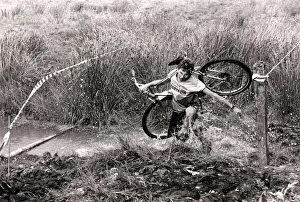 00362 Prints: Mind how you go... a competitor carries his cycle across one of the many bogs negotiated