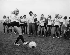 Wags Prints: Miss Eva Haralsted takes a penalty shot under the watchful eye of fiancee George Best