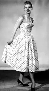 Model from 1950s wearing a dress with a fitted corset style top with a tiny waist