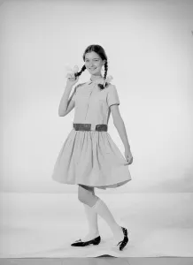 Model Jennifer Goddard. Brown-haired girl in checkered dress with pig tails