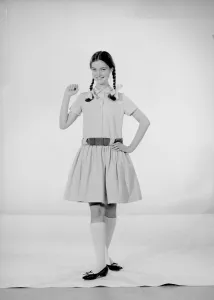 Model Jennifer Goddard. Brown-haired girl in checkered dress with pig tails