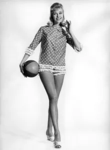 Model Jo Waring wearing a polka dot patterned top and holding a beach ball