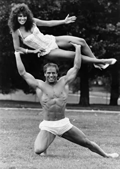 Model Linda Lusardi being lifted by nearly naked muscley strong man Julien Moss in
