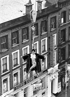 Stunt Prints: Model Linn Yamazaki demostrating the strength of her hair by hanging above rooftops on a
