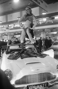 Fur Coat Prints: Model poses on the bonnet of a Aston Martin Volante at Motor Show 15th October 1968