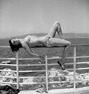 Model posing wearing a bikini lying on railing circa 1949