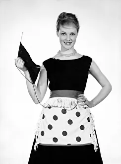 00355 Prints: Model Roma Reeves seen here wearing green spot apron whislt knitting 1958 B944-002