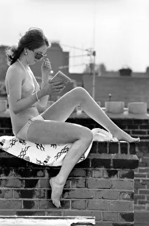 A model wearing a bikini reading a book as she sunbathes on a rooftop on Kings Road in