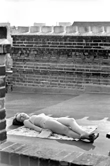 A model wearing a bikini as she subathes on a rooftop on Kings Road in Chelsea, London