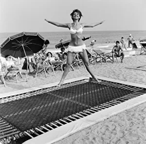 Fitness Prints: A model wearing bikini swimwear bounces on a trampoline on a beach in the French Riviera