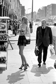 A model wearing a polo neck long sleeved top with tartan skirt shopping for shoes