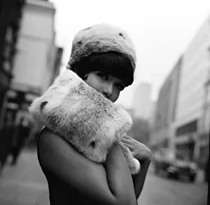 A model wears a fur hat and muff Fashion June 1965 hiding the lower part of her