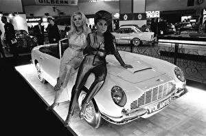 Models pose on the bonnet of a Aston Martin Volante at Motor Show 18th October 1966