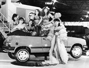 Models pose in South American dress next to the latest model to come from car makers