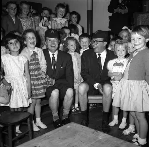 Morecambe & Wise with children of the Hamlet of Ratcliff school Stepney London wearing