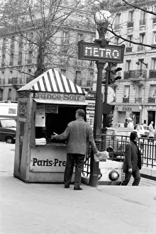 A Morning newspaper reader picks up his paper from a kiosk in the 15th district of Paris