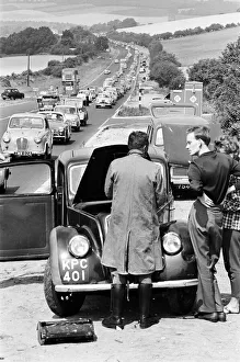 Queue Prints: Motor mechanic seen here trying to repair a broken down car as heavy August Bank