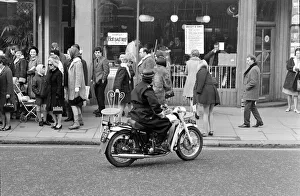A motorcycle policeman orders three models wearing swimsuits sitting outside Guys