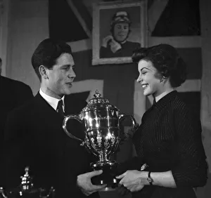 Motorcycling Prints: Motorcycle racing champion Geoff Duke shows the trophy to film star Joan Rice
