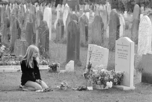 Kneeling Prints: Mourner Margaret Lowe kneels at the grave stone of former Rolling Stones guitarist Brian