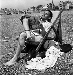 00013 Prints: Mr C Reed reading the Reveille paper whilst smoking cigarette in an unusual cigarette