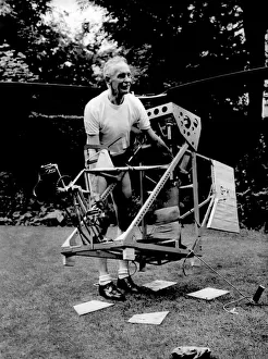 Mr. Harry Killick carries his home built man powered helicopter back to his workshop