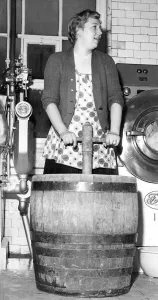 Mrs. Hedley demonstrates the old post-tub method of washing clothes, in February 1960
