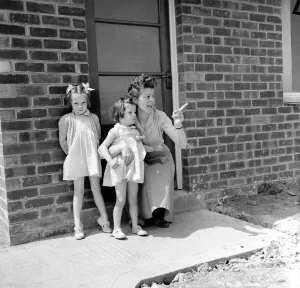 Mrs. Kirby and her daughters, Carol, 5, and Sandra, 4, outside their council house today