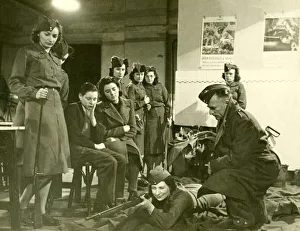 Aiming Prints: Mrs Olive carson taking rifle training instruction from Instructor while two of her