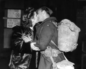 00095 Prints: Mrs Wells of Leigh On Sea greets her husband with a kiss at the railway station after