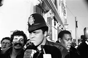 00328 Prints: Muhammad Ali seen here on a visit to the UK poses wearing a policemans helmet