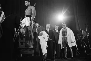 Muhammad Ali stands on the scales as Brian London looks on at the weigh-in ahead of their
