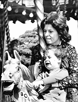 Fairground Rides Prints: A mum grips on tight to her little girl who is having trouble coming to terms with