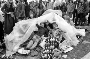 Music Fans hiding under a plastic sheet to avoid the rain at the Bath Festival of Blues