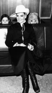 Natalie Wood waits for her flight at London airport peeping pver the seats are her