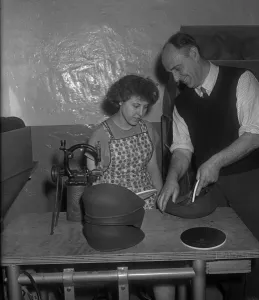 A new employee being shown how to insert a inner liner into a flat cap at the Denham