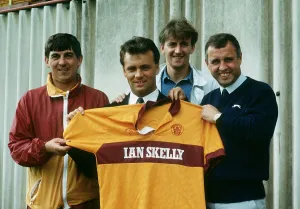 Transfer Prints: New Motherwell signing Davie Cooper poses with the team shirt as he stand with management