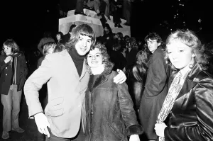 00753 Prints: New Year revellers pose for the camera while in the background revellers climb the statue