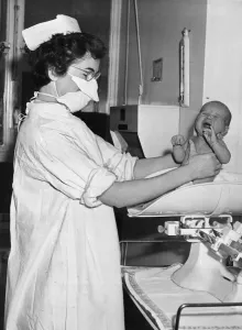 00176 Prints: A nurse pictured holding and weighing a baby December 1956