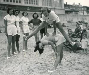 Leaping Prints: Ocean chorus girls playing leap frog on a beach at Clacton on Sea Playing