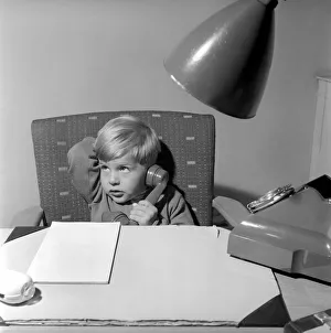 Office Junior: Two year old boy helps out at the offices of Theobald and son. 1957