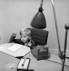 Office Junior: Two year old boy helps out at the offices of Theobald and son. 1957