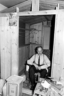 Old man inside a wooden shed. Jim Phillips at home in his little wooden hut