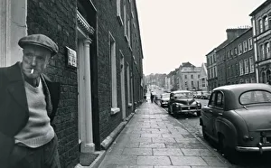 Pensioner Prints: An old man standing in a doorway, smoking Street scene Georgian buildings
