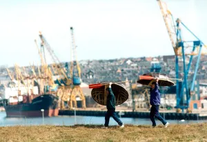 Oars Prints: Old and new, Danny Gilchrist and Dave Potts carry thier coracles with a backdrop of