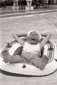 Old woman in an inflatable dinghy in a swimming pool August 1984