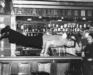 Actions Prints: Oliver Reed actor doing press-ups on the bar at the Jamaica Inn Guernsey Currently