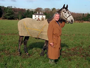 Oliver Reed actor wearing brown long coat standing in field with his horse Bobby at home