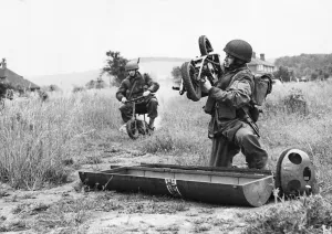 1943 Prints: A paratrooper lifts a folding motor scooter from its parachute container